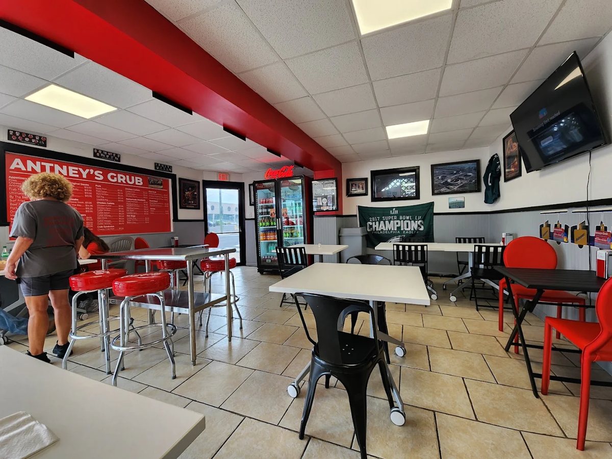 Indoor dining area with red accent ceiling beam, stools, tables, and the red menu board on the wall
