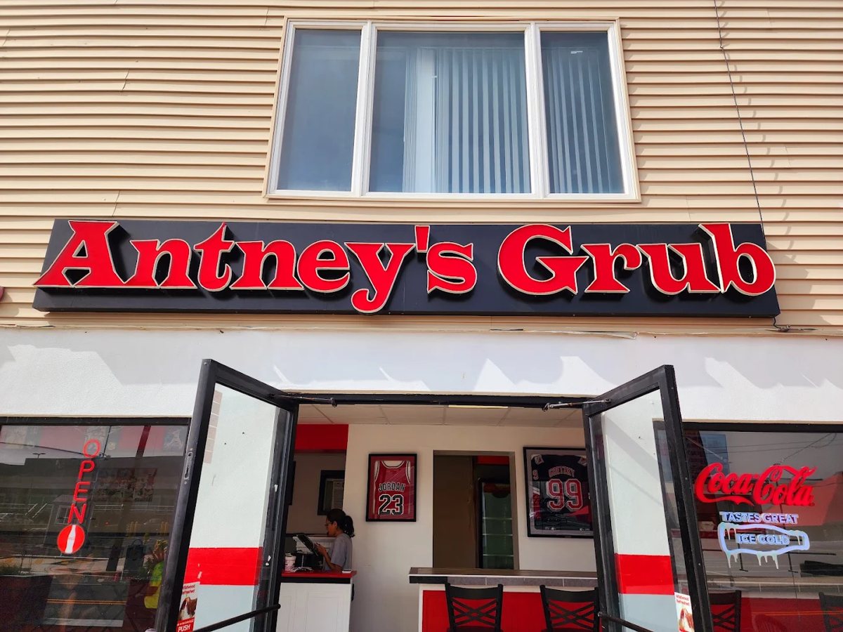 Open front doors of Antney's Grub with the illuminated sign, framed Jordan and Gretzky jerseys, and order counter visible inside